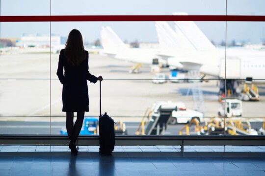 Traveler at airport window earning Bilt Points on rent and mortgage payments with Bilt Card 2.0