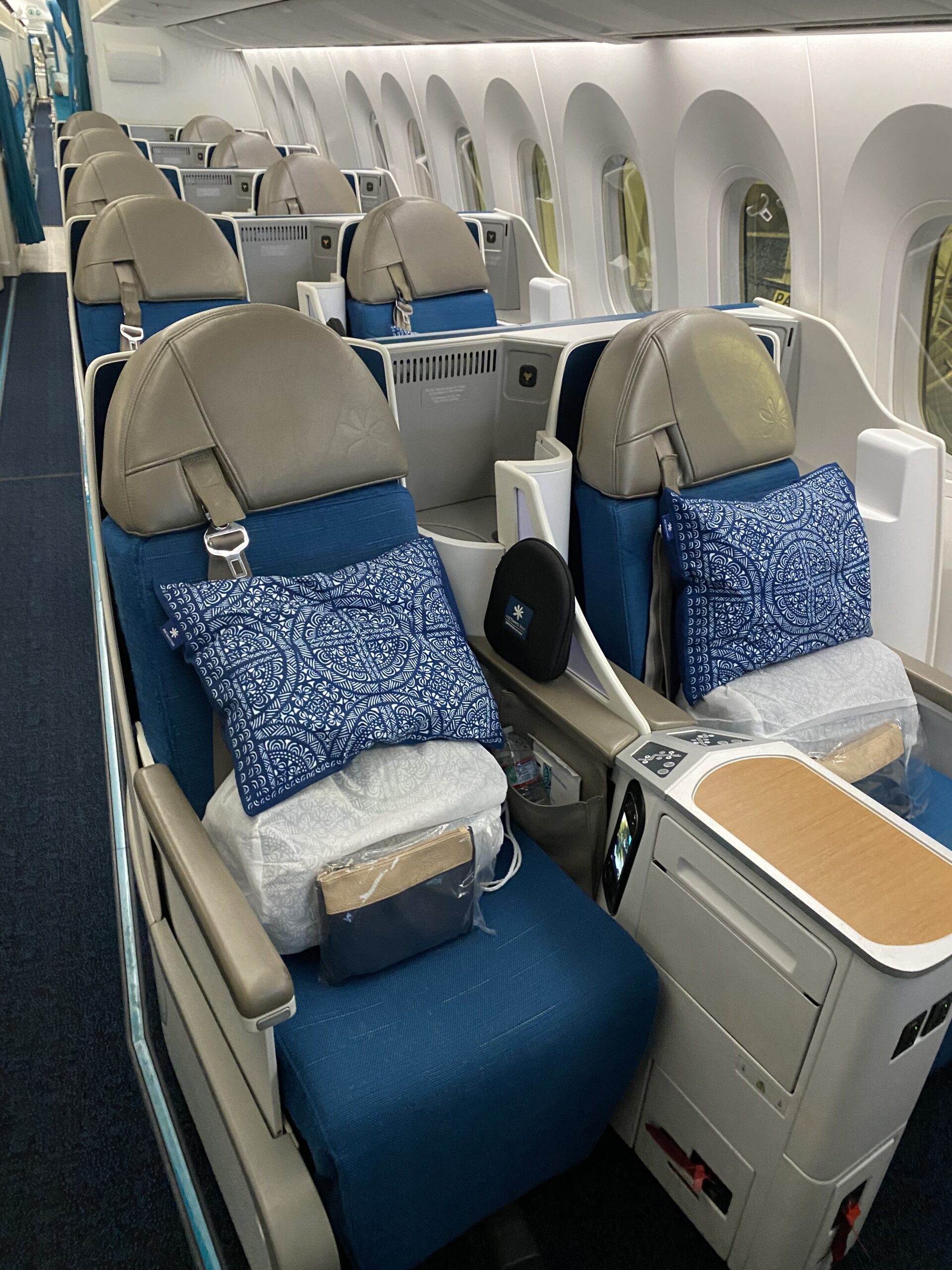 Our pair of Poerava Business seats before takeoff — Tahitian pillow, folded duvet, sealed amenity kit, and slippers already waiting