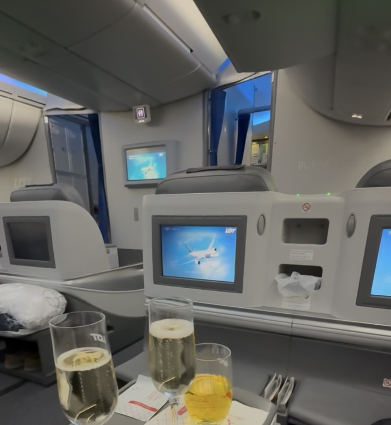 Champagne on the tray table looking forward through LOT 787 business class