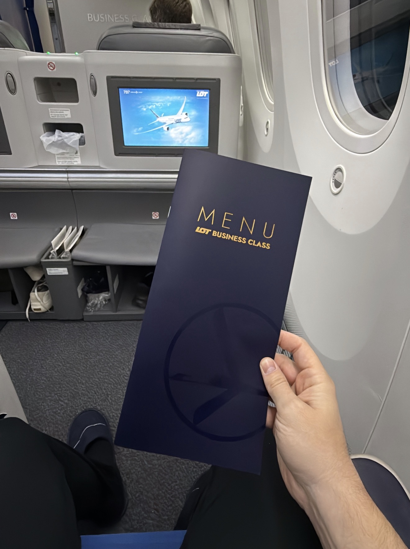 LOT Business Class menu held up in front of the 787 seat-back screen